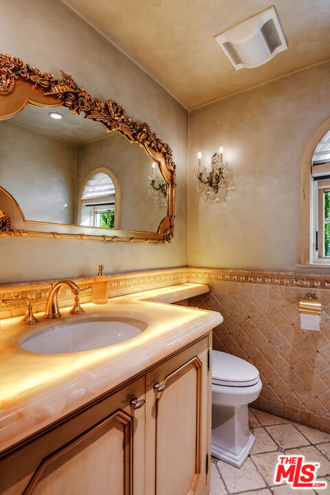 bathroom with vanity, toilet, tile walls, and plenty of natural light