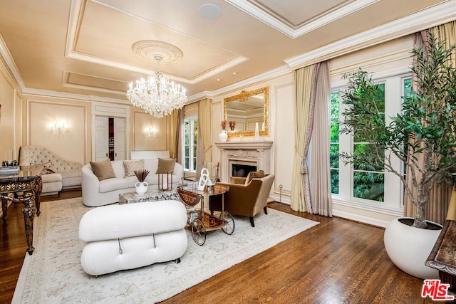 interior space featuring crown molding, dark wood-type flooring, a tray ceiling, a fireplace, and a chandelier