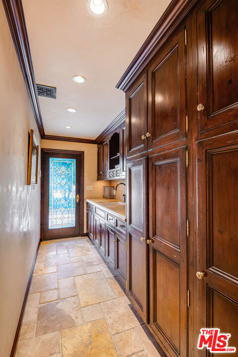 kitchen featuring ornamental molding, dark brown cabinets, and sink