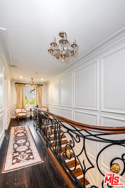 hall featuring crown molding, dark hardwood / wood-style floors, and a chandelier