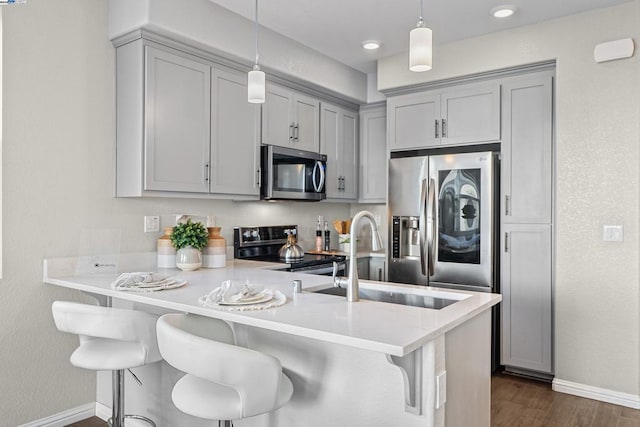 kitchen featuring decorative light fixtures, a breakfast bar area, stainless steel appliances, and kitchen peninsula