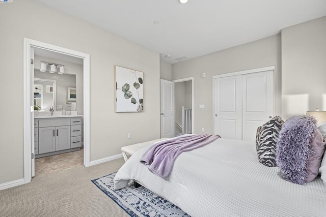 bedroom featuring light colored carpet, connected bathroom, sink, and a closet