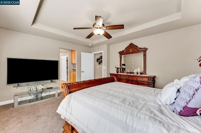 carpeted bedroom featuring ceiling fan, ensuite bathroom, and a raised ceiling