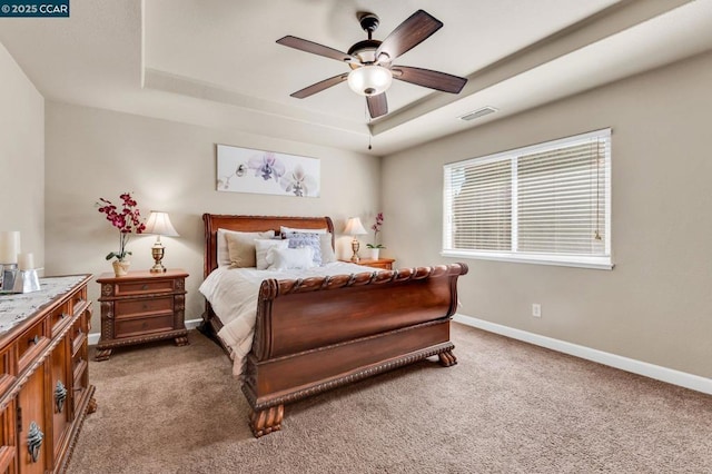 bedroom featuring ceiling fan, a raised ceiling, and carpet