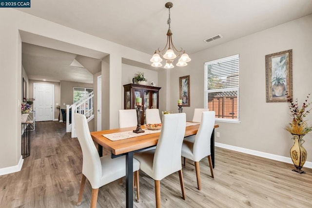 dining space with hardwood / wood-style flooring, a healthy amount of sunlight, and an inviting chandelier