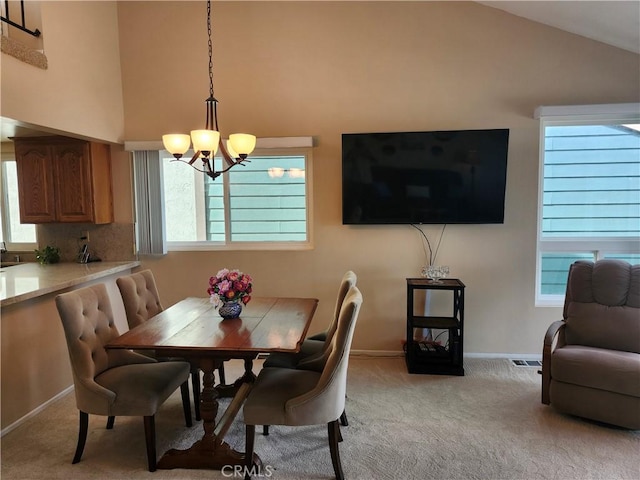 carpeted dining space with a notable chandelier, plenty of natural light, and high vaulted ceiling