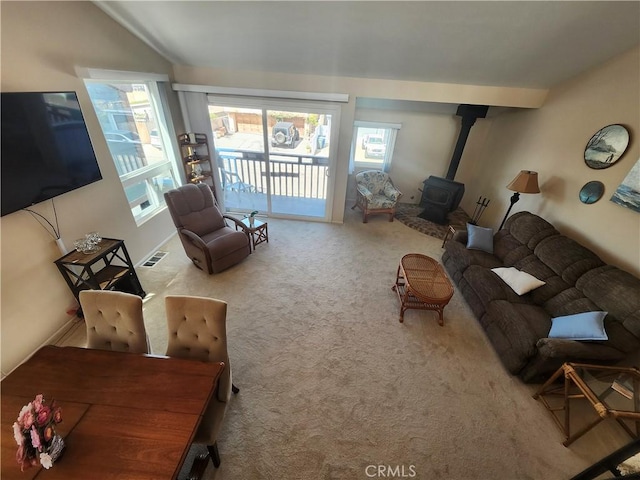 carpeted living room with vaulted ceiling and a wood stove