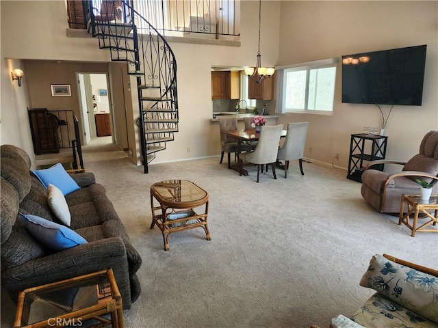 living room with a notable chandelier, a towering ceiling, and light colored carpet