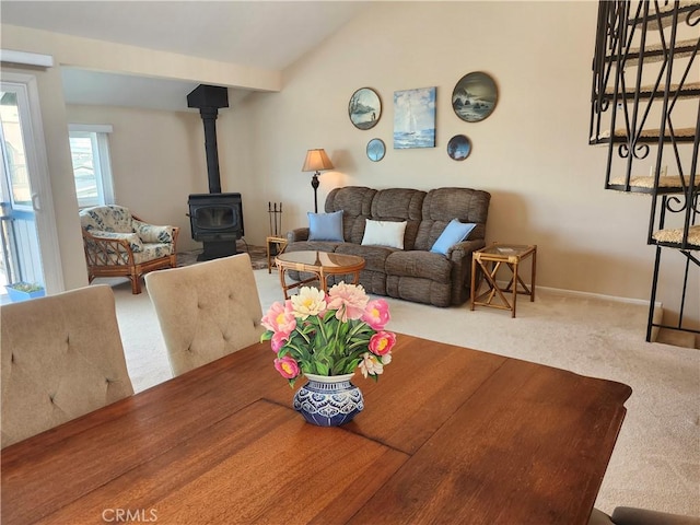 carpeted dining room featuring lofted ceiling with beams and a wood stove