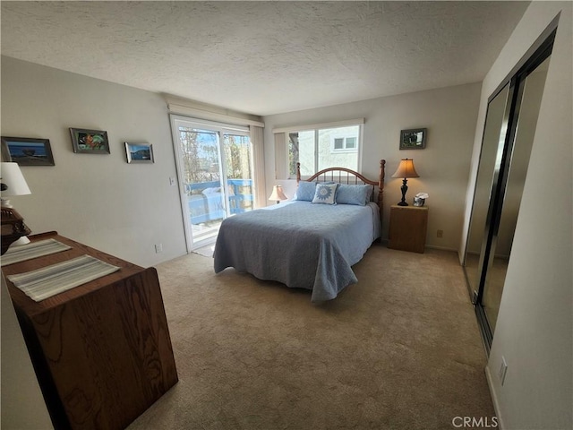 carpeted bedroom with a textured ceiling and access to outside