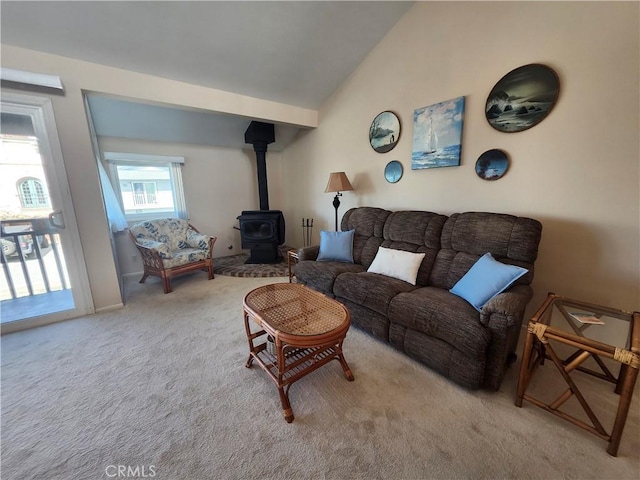 carpeted living room with lofted ceiling and a wood stove