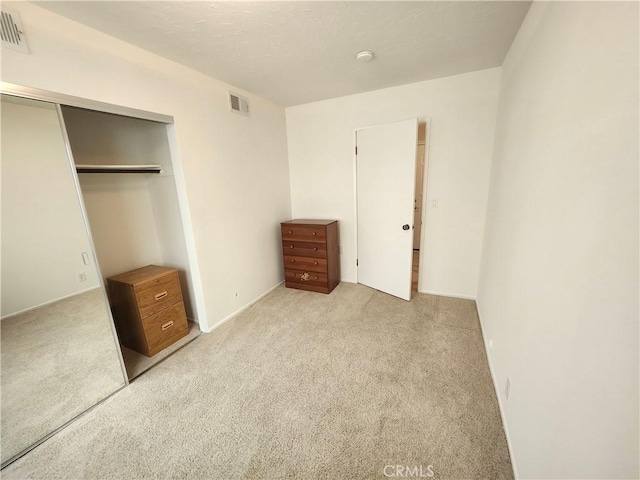 unfurnished bedroom with light colored carpet and a closet