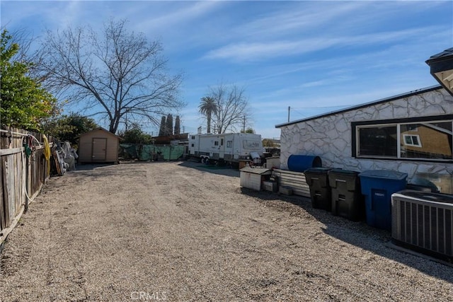 view of yard with central AC and a storage shed