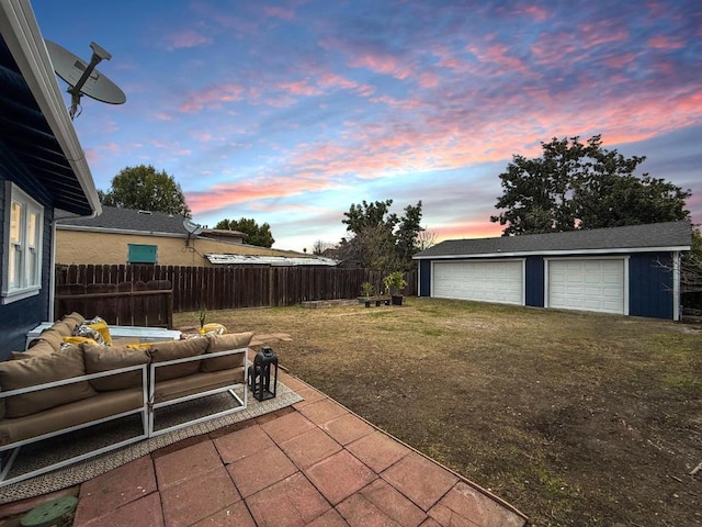 yard at dusk with a garage, an outdoor structure, an outdoor living space, and a patio area