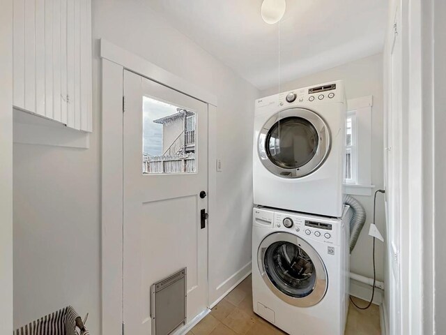 washroom with stacked washer and dryer and light tile patterned floors