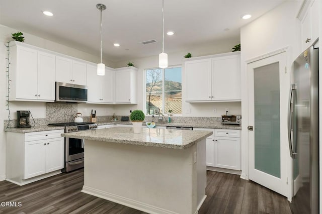 kitchen featuring a kitchen island, appliances with stainless steel finishes, pendant lighting, and white cabinets