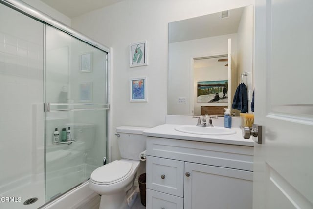 bathroom featuring vanity, toilet, and a shower with door