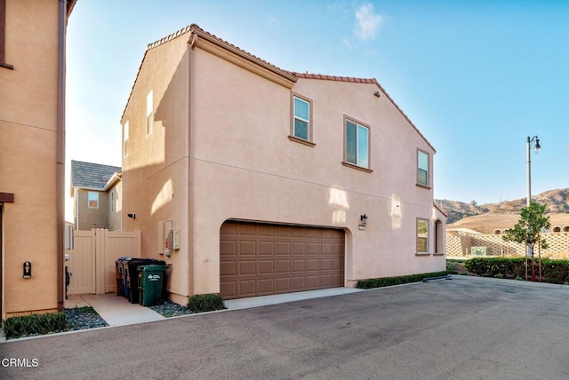 view of front of property with an attached garage, fence, a mountain view, and stucco siding