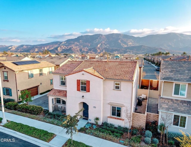 view of front of home with a residential view, a tile roof, a mountain view, and stucco siding