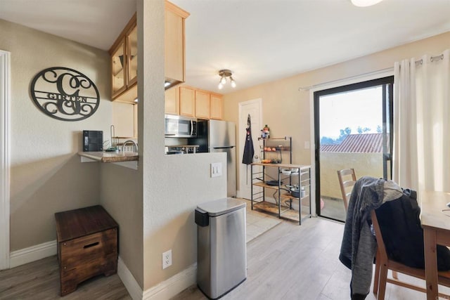 kitchen featuring stainless steel appliances, light hardwood / wood-style flooring, and light brown cabinets