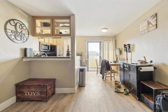 interior space with refrigerator, light hardwood / wood-style floors, and kitchen peninsula