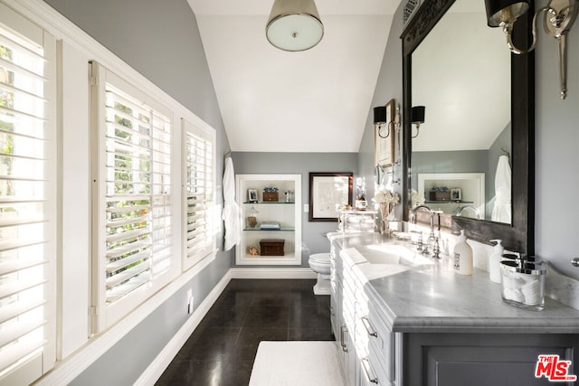 bathroom with tile patterned flooring, vanity, lofted ceiling, and toilet