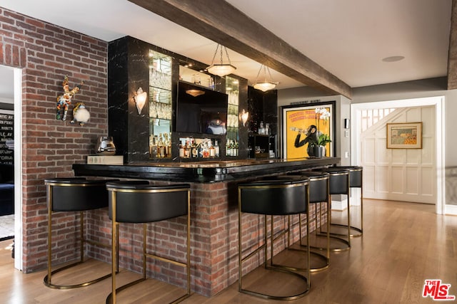 bar featuring hardwood / wood-style flooring, decorative light fixtures, and beamed ceiling