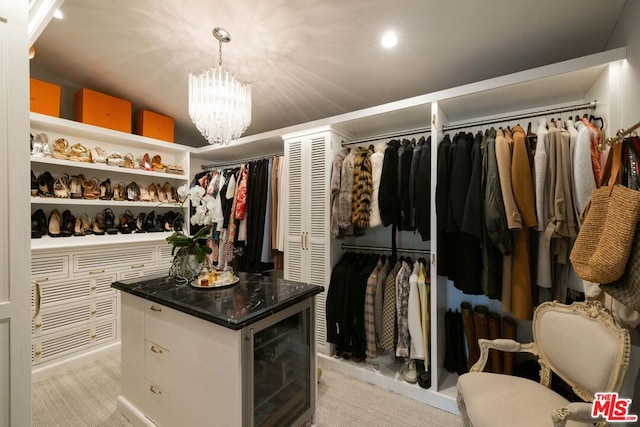 walk in closet featuring light colored carpet and a notable chandelier