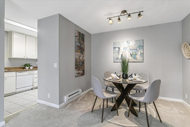 dining space with a baseboard radiator, light colored carpet, and track lighting