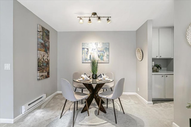 dining area with a baseboard heating unit, light colored carpet, and track lighting