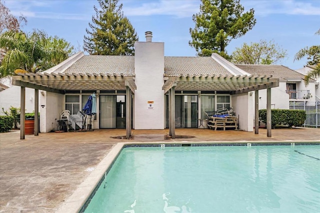 rear view of house with a community pool, a pergola, and a patio