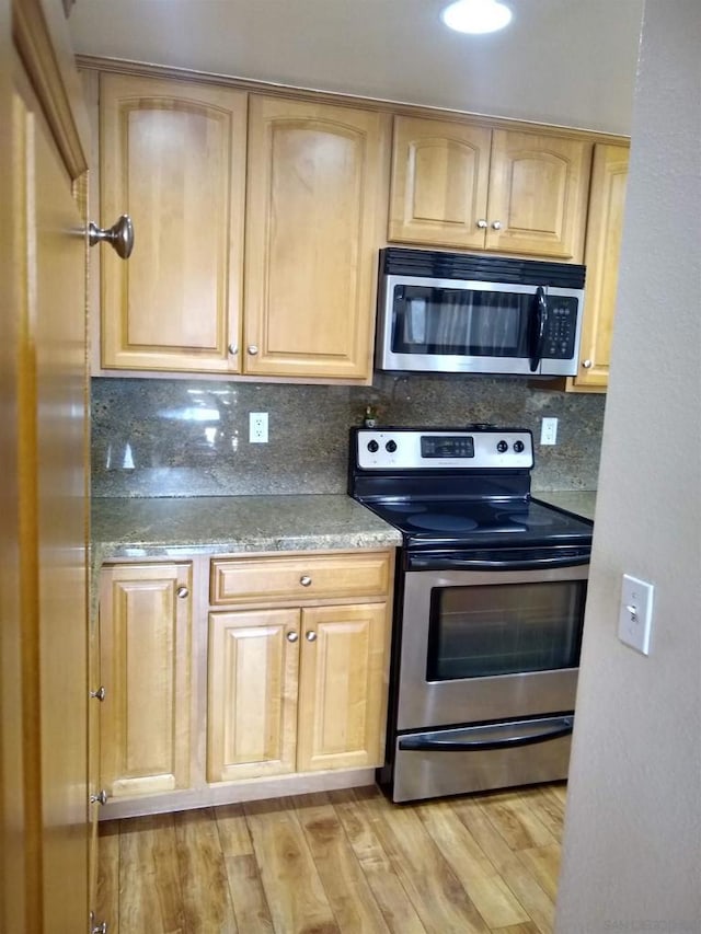 kitchen with appliances with stainless steel finishes, light brown cabinets, light wood-type flooring, and decorative backsplash