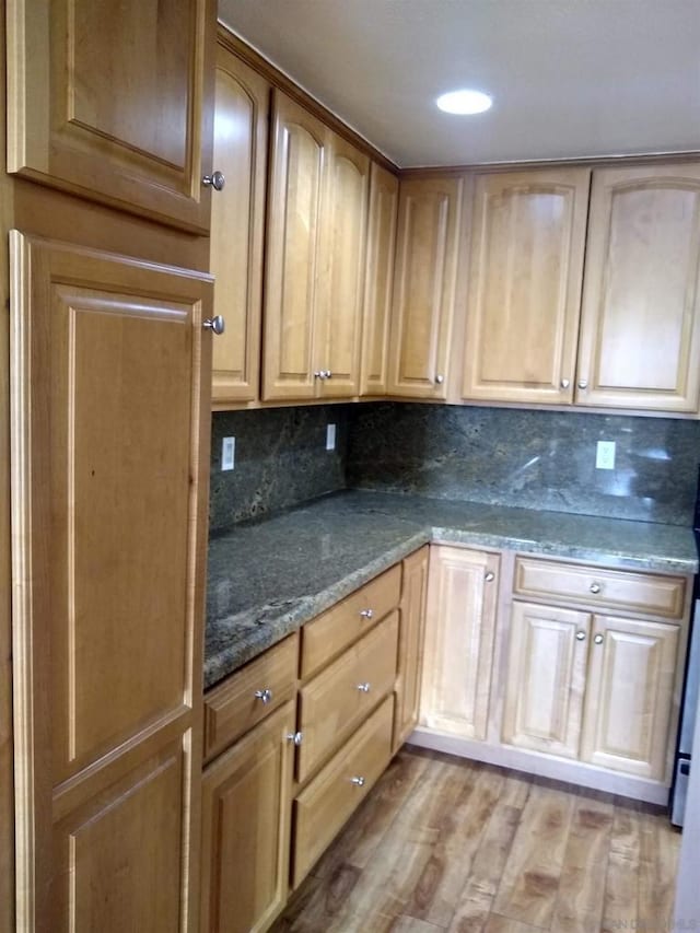 kitchen featuring tasteful backsplash, dark stone counters, and light wood-type flooring