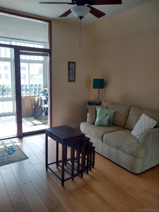 living room featuring ceiling fan, light wood-type flooring, and a wall of windows