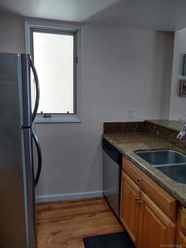 kitchen with appliances with stainless steel finishes, sink, plenty of natural light, and light hardwood / wood-style flooring