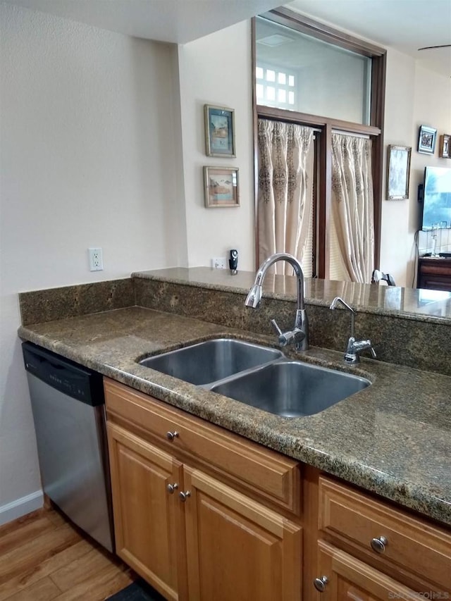 kitchen featuring dark stone countertops, sink, stainless steel dishwasher, and light hardwood / wood-style floors