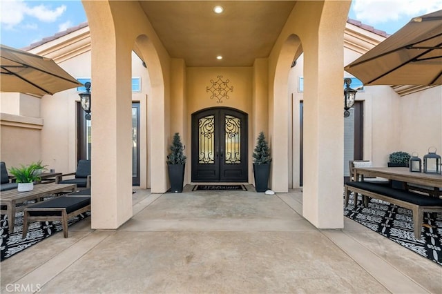 entrance to property with a tiled roof, french doors, a patio area, and stucco siding