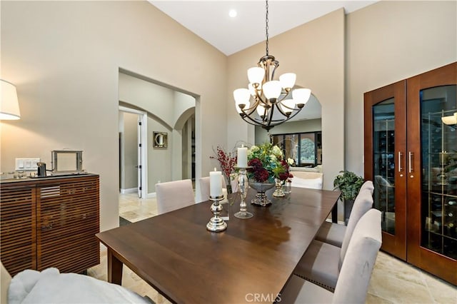 dining room with an inviting chandelier, arched walkways, high vaulted ceiling, and french doors