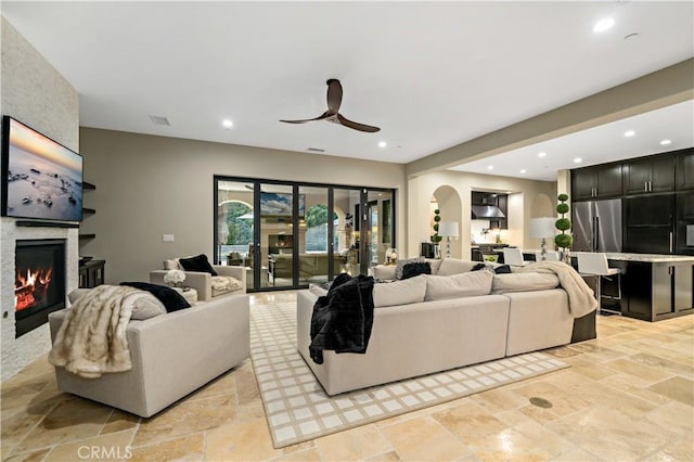 living area with a large fireplace, arched walkways, and recessed lighting