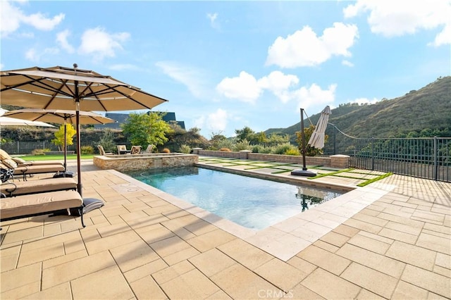 view of swimming pool featuring a patio, fence, and a mountain view