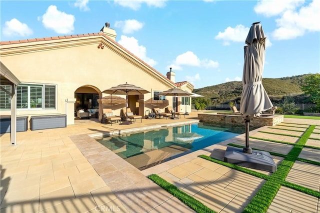 view of pool with a mountain view, a patio, a fenced in pool, and an in ground hot tub