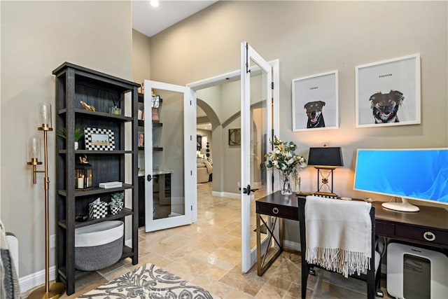 office area featuring arched walkways, stone finish flooring, french doors, and baseboards