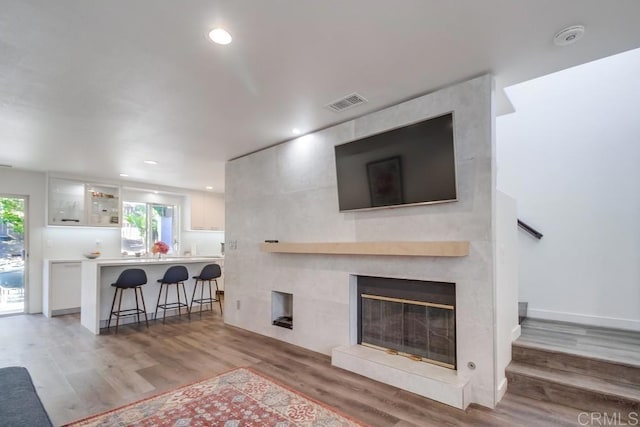 living room featuring hardwood / wood-style flooring, a tile fireplace, and a healthy amount of sunlight