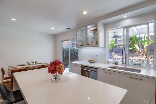 kitchen with sink, white cabinetry, a center island, stainless steel dishwasher, and a kitchen breakfast bar