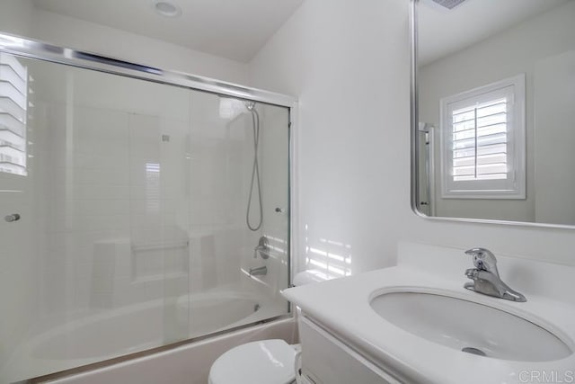 full bathroom with enclosed tub / shower combo, vanity, and toilet