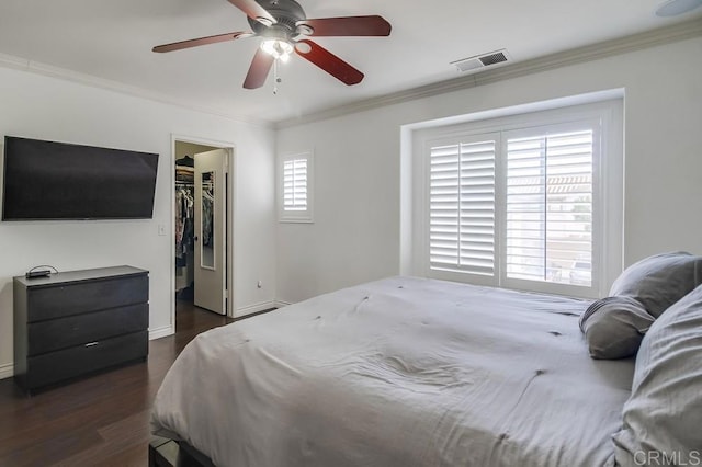 bedroom featuring a walk in closet, ornamental molding, dark hardwood / wood-style floors, and a closet