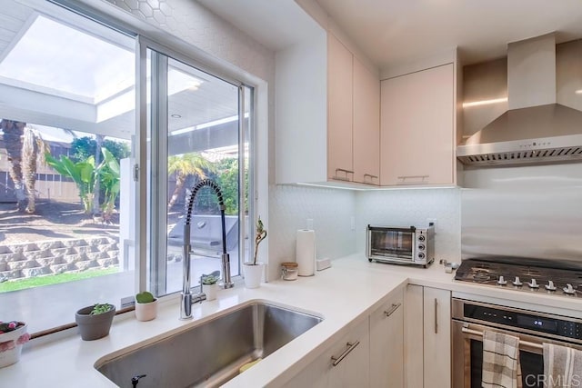 kitchen featuring white cabinetry, appliances with stainless steel finishes, sink, and wall chimney exhaust hood