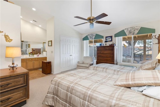 bedroom with ensuite bath, ceiling fan, light carpet, vaulted ceiling, and a closet