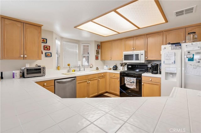 kitchen with sink, white appliances, kitchen peninsula, and light brown cabinets