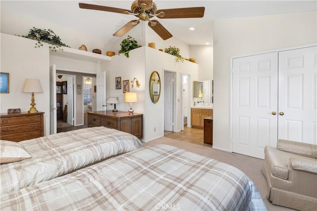 carpeted bedroom with ensuite bathroom, lofted ceiling, ceiling fan, and a closet